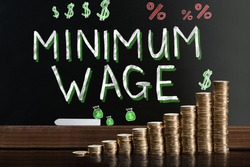Minimum Wage At Blackboard Behind Stacked Coins