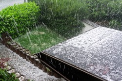 Hail falls on a house roof during a hailstorm