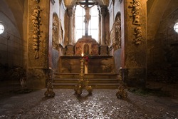 Altar in old church ossuary with human skulls and bones on walls, Kutna Hora, Czech Republic.