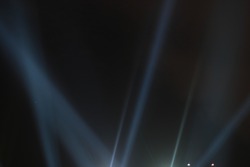 Abstract background. Searchlights shining beams of light into the black sky.