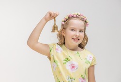 Happy schoolgirl with bell smiling and ringing while looking at camera