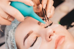Eyelash extensions - the master dries glue with air - painstakingly delicate work