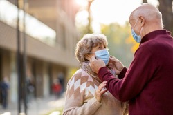 Senior couple wearing protective face masks outdoors 
