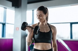 Young woman exercising with dumbbells in a health club
