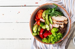 Buddha bowl dish with chicken fillet, quinoa, avocado, sweet pepper, tomato, cucumber, radish, fresh lettuce salad and sesame. Detox and healthy superfoods bowl concept. Overhead, top view, flat lay
