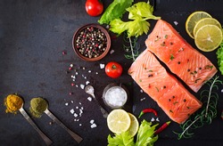 Raw salmon fillet and ingredients for cooking on a dark background in a rustic style. Top view