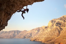 Female rock climber on overhanging cliff, Kalymnos Island, Greece 