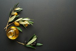Olive oil and olive branch on black background