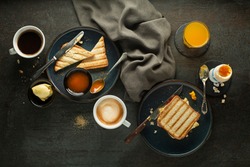 Breakfast served with coffee, juice, toast sandwich, boiled egg, and jam with butter. Delicious healthy breakfast.