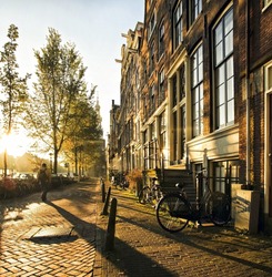 A stranger in the streets of the city Amsterdam, accompanied by long shadows, strolled between the canals and residential houses during this atmospheric sunset.