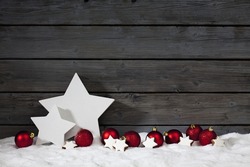 Star shaped christmas decoration christmas bulbs cinnamon stars on pile of snow against wooden wall