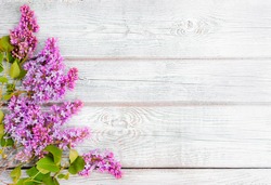spring lilac flowers and a straw hat on a white wooden background are a free place to insert text. minimalism, design, top view. flatley