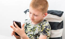 young boy is listen music with the mobilephone on the sofa