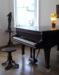 light room: grand piano near the window, round stool, in the background - two statuettes