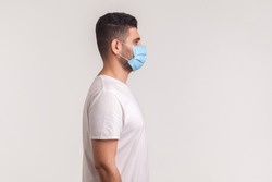 Side view of man wearing hygienic mask to prevent infection, respiratory illnesses such as flu, 2019-nCoV. indoor shot isolated, copy space for advertise about coronavirus, Covid-19prevention awarenes