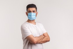 Effective protection against coronavirus. Man holding hands crossed and wearing hygienic mask to prevent infection, respiratory illness such as flu, 2019-nCoV, Covid-19. indoor studio shot, white back