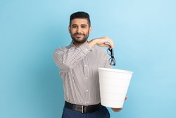 Portrait of smiling happy satisfied businessman throwing out his optical glasses after vision treatment, looking at camera, wearing striped shirt. Indoor studio shot isolated on blue background.