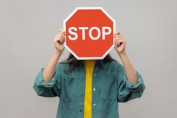 woman holding stop sign on gray background. 