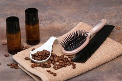 Caffeine shampoo with coffee beans, hairbrush and comb on a towel.