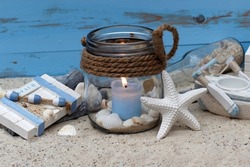 Maritime decoration with a candle, starfish and shells in the sand.