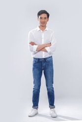 Full body Portrait of young man wearing white shirt with jeans standing posing in studio