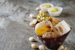 Eastern sweets. Turkish delight with pistachios in a vase. Dark stone background.