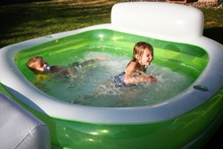Two toddlers splashing around in a swimming pool