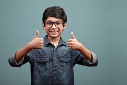 Happy boy of Indian ethnicity shows thumbs up gesture with both hands