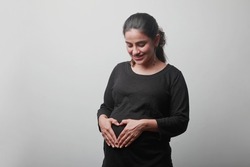 Young woman expecting a baby affectionately touches her tummy