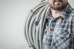 Caucasian Electric Construction Worker in His 30s with Conduit Pipe on His Shoulder Close Up. Industrial Theme.