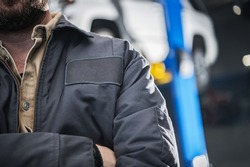 Closeup of Professional Caucasian Mechanic Wearing Grey Work Jacket with Copy Space Patch for Logotype.