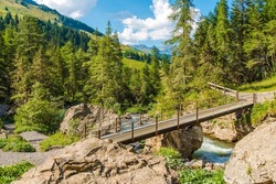 Adelboden Switzerland Landscape. Mountain River and the Summer Mountain Landscape. Small Trail Bridge.