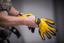 Wearing Construction Safety Gloves Closeup Photo. Caucasian Contractor Preparing For a Job.