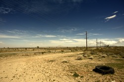 Outback California USA - California Suburbs Desert Landscape with Old Broken Tire on the Road Side.