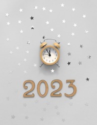 Party Time Layout with Little Gold Clock, Numbers 2023 and Silver Confetti of Star Shape on a Light Gray Background. Top-Down View. Flat Lay Composition ideal for Banner, New Years Wishes, Card.