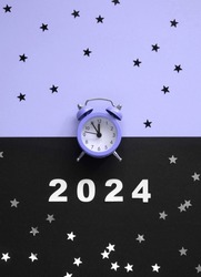 Happy New Year. Party Time Layout with Little Alarm Clock, Numbers 2024 and Silver Confetti of Star Shape on a Violet-Black Background. Top-Down View. Flat Lay ideal for Banner, New Years Wishes,Card.