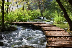 Wooden footbridge across stream in the mountain forest, Croatia.