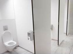 Clean white Public Washroom WC stall with white plastic toilet bowl seat inside with open lid