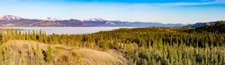 Hi-res panoramic landscape view of still frozen ice-covered Lake Laberge in spring May boreal forest tiaga of Yukon Territory, Canada