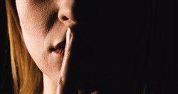 Seriouse woman placing her finger on lips - keep silence or secret. Mouth close up