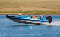 Man driving a fast boat with panned (motion blur) background.