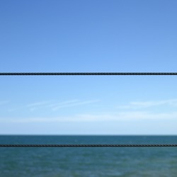 Blue ocean viewed from a metal wired fence