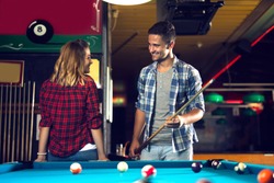 Couple dating, flirting and playing billiard in a pool hall