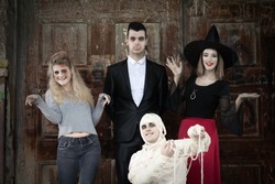 Zombie, vampire, witch and mummy standing in front of the door of the haunted house