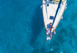 Aeiral view of Happy family with adorable daughter and son resting on a big yacht. Drone photography