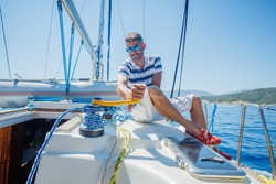 Young man sailing yacht steering wheel vacation sail. Holidays, people, travel