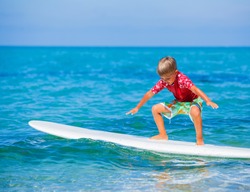 Little boy with surf board learning surfing