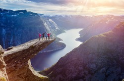 Happy Family On Trolltunga - View On Norway Mountain Landscape At Sunset From Trolltunga - The Troll's tongue in Odda, Ringedalsvatnet Lake, Norway.