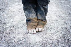 dirty and bare child's feet on gravel. Poverty concept