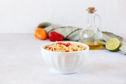 Quinoa cooked with red and yellow mini bell peppers, in a white bowl